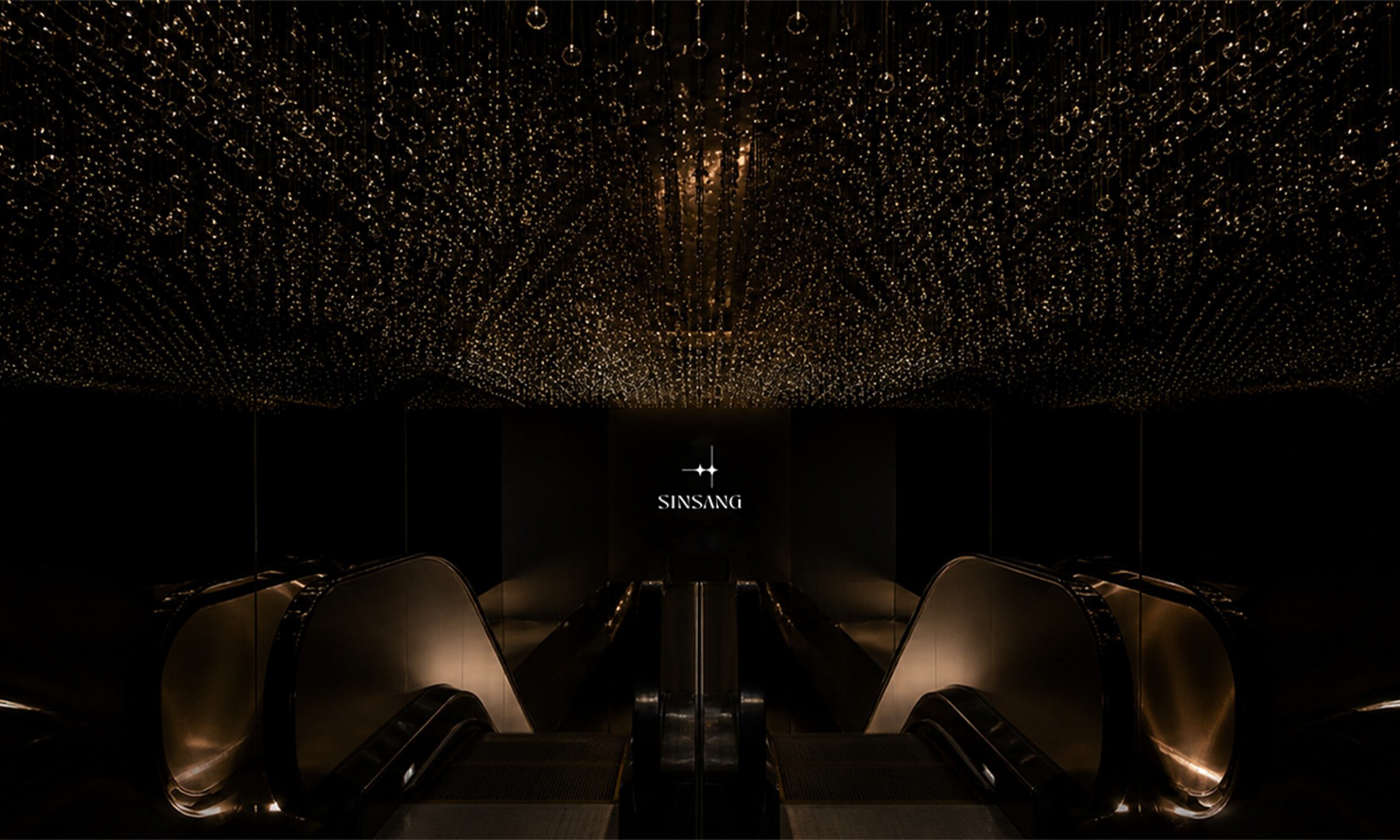 Dark entrance with a chandelier ceiling, SINSANG logo and escalator