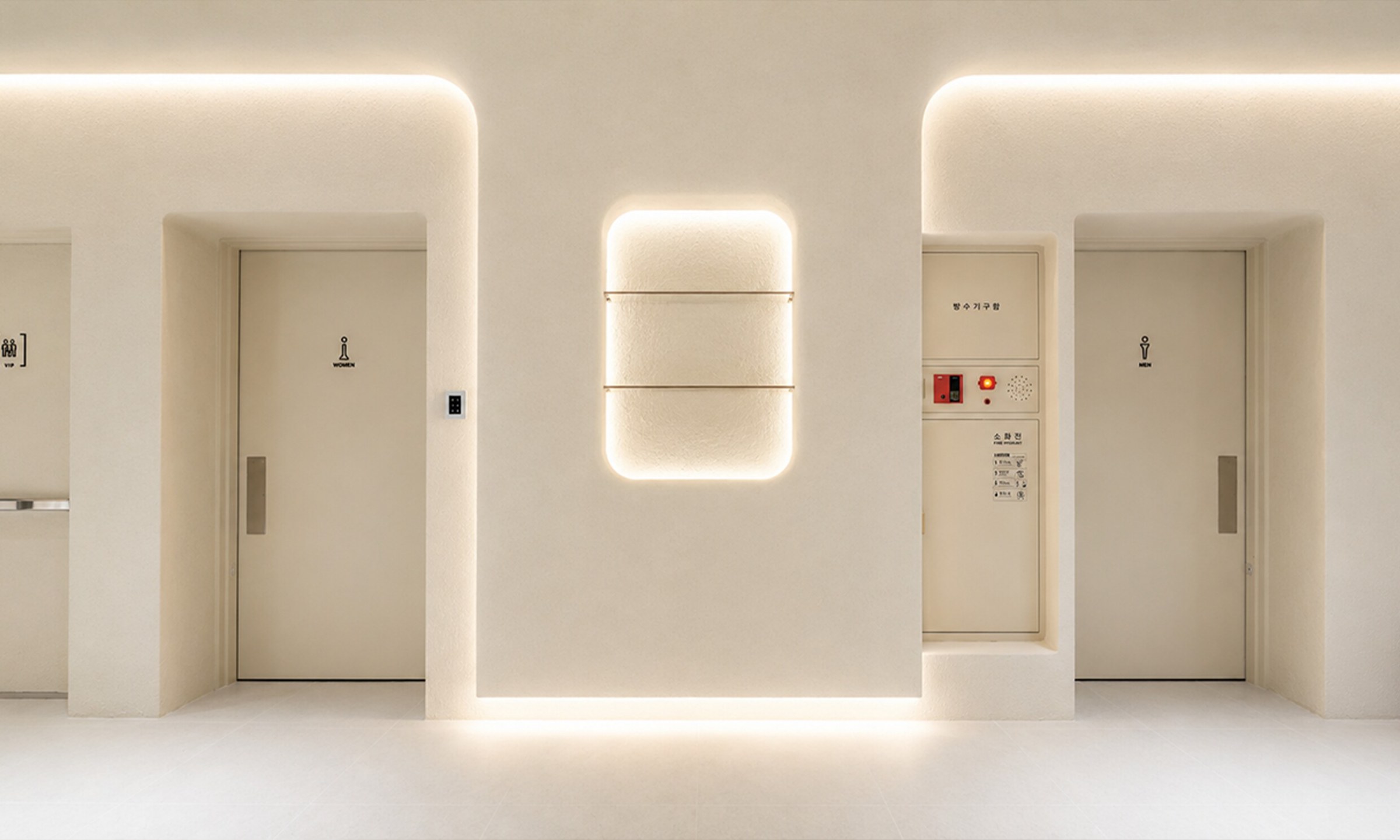 Wall with a restroom sign inside an indirectly lit arch
