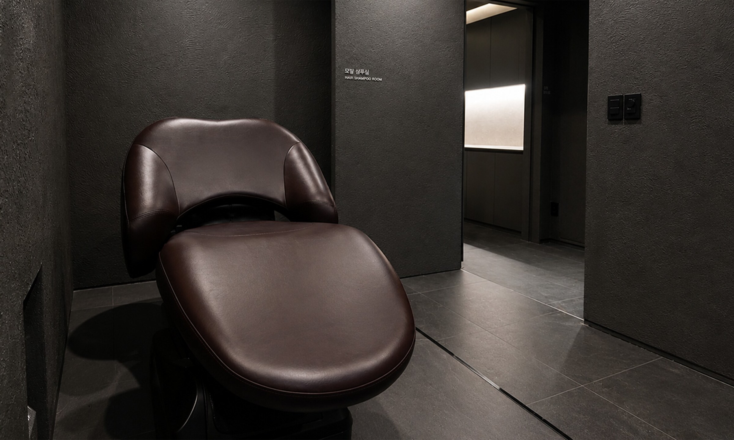 Dark shampoo room with brown leather shampoo chairs