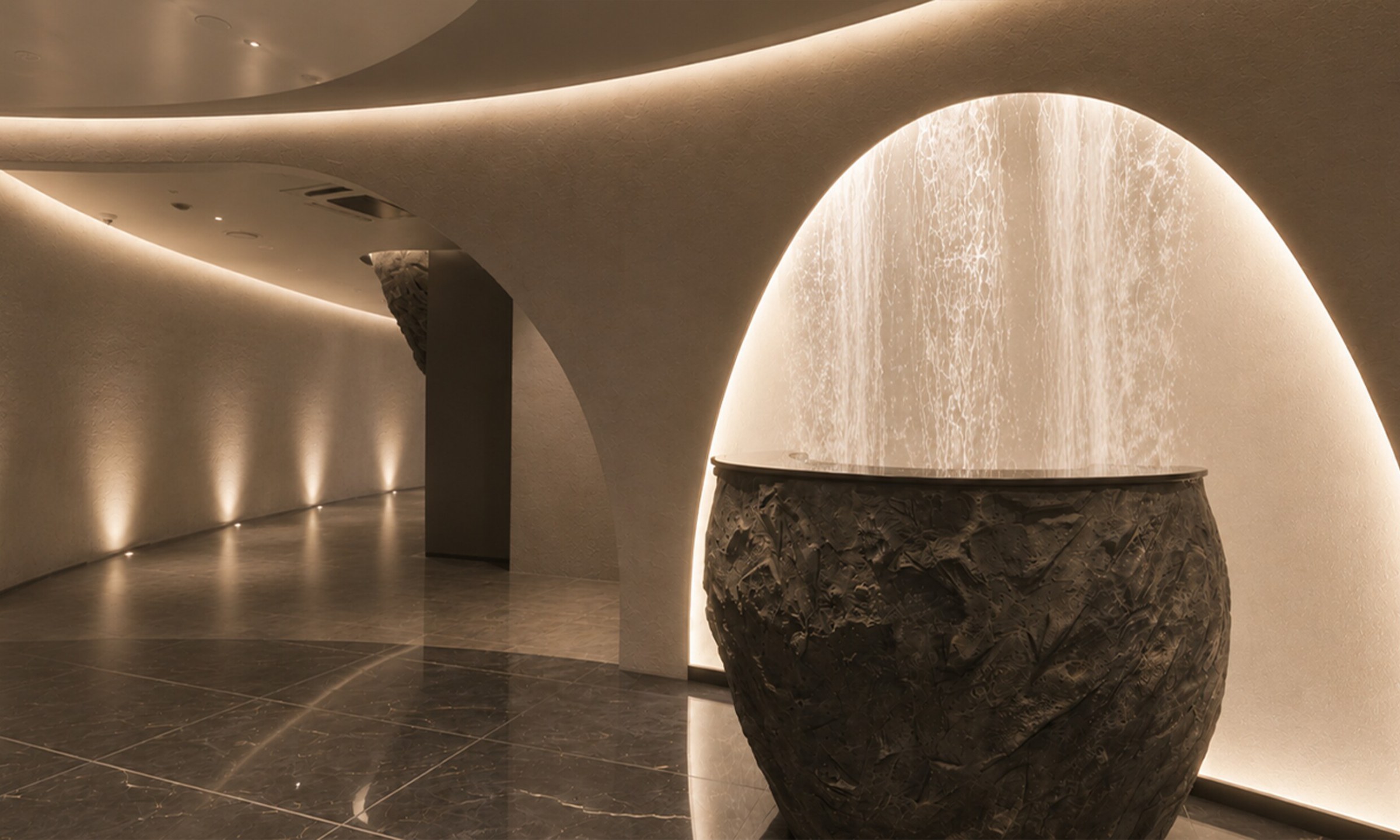 Hallway with a stone planter-style water sculpture in an arch